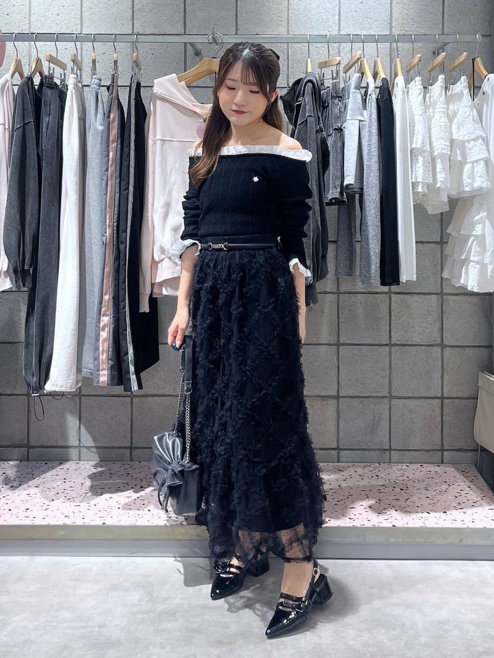 グレー系のショルダーバッグ、ブラック系のパンプス、ブラック系のスカートを着用したレディースの春コーディネートの2枚目の写真