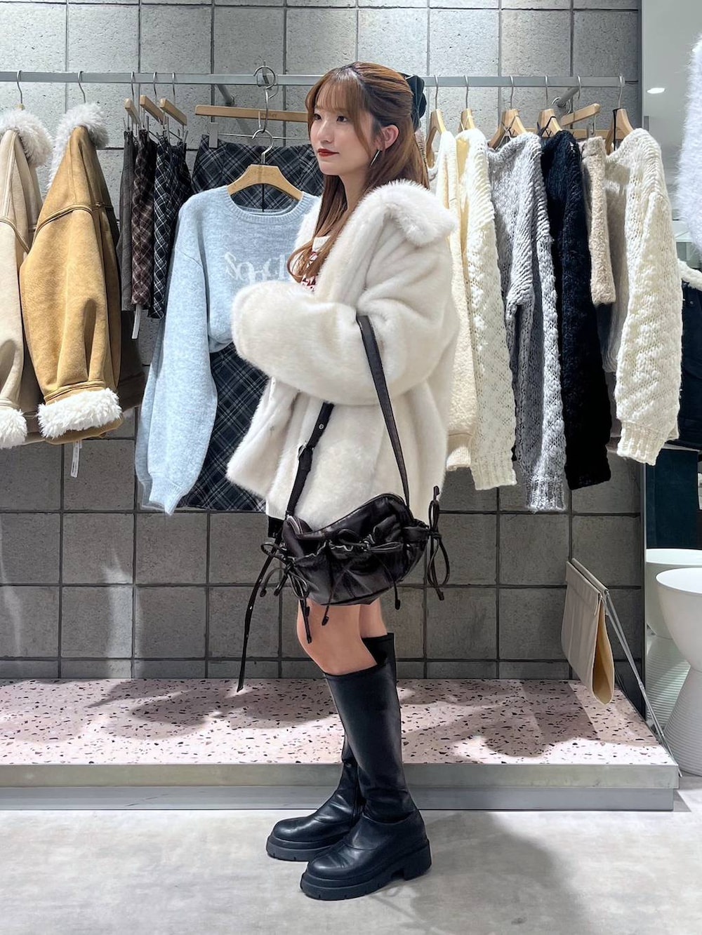 ブラック系のブーツ、ブラック系のスカート、ブラック系のショルダーバッグを着用したレディースの冬コーディネートの4枚目の写真