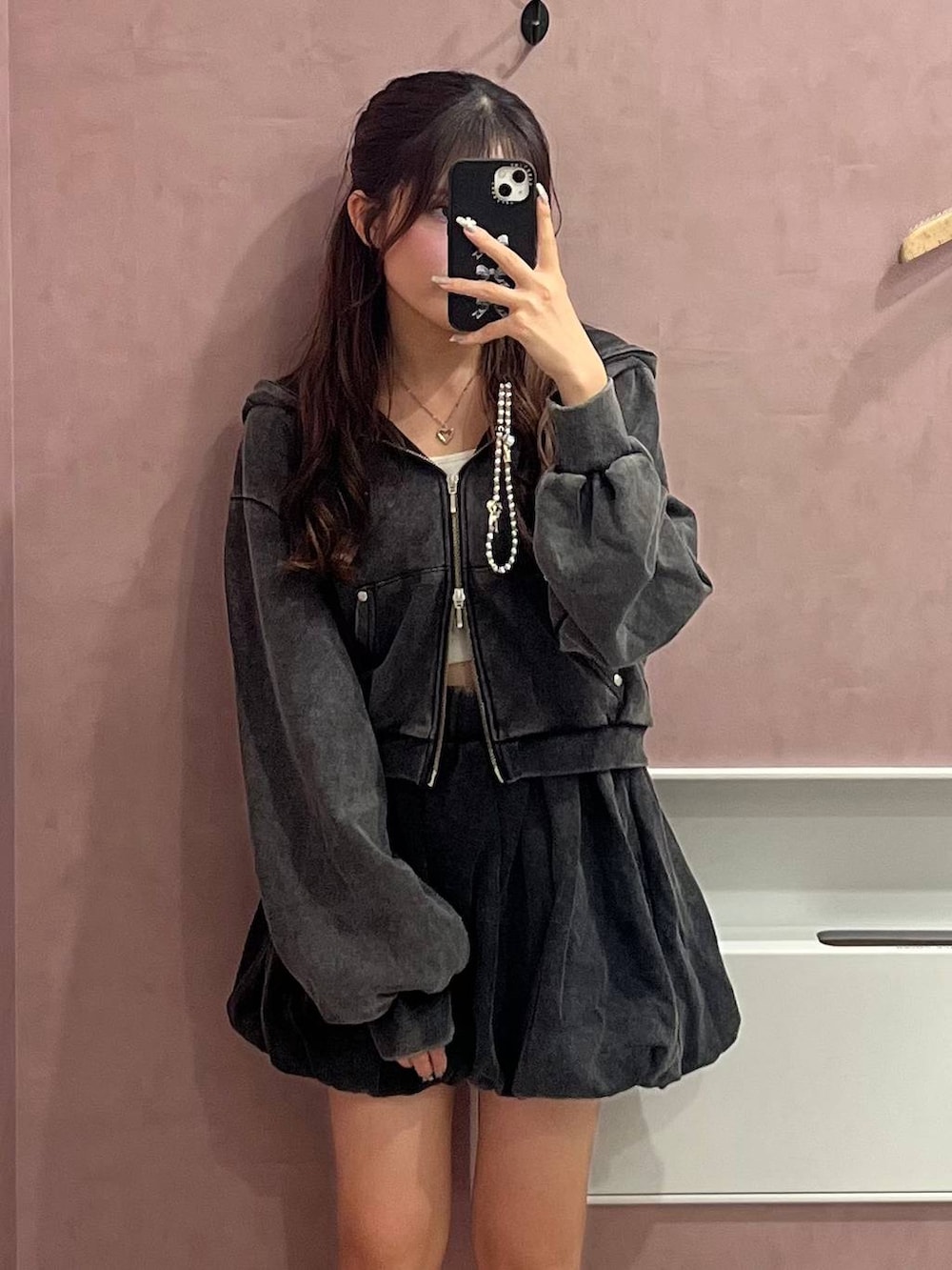 ホワイト系のキャミソール、ブラック系のスカート、ブラック系のパーカーを着用したレディースの秋コーディネートの2枚目の写真