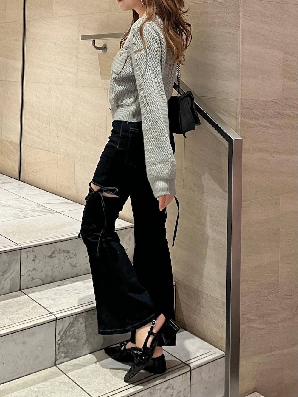 グレー系のショルダーバッグ、ブラック系のパンプス、ブルー系のデニムパンツを着用したレディースの春コーディネートの6枚目の写真