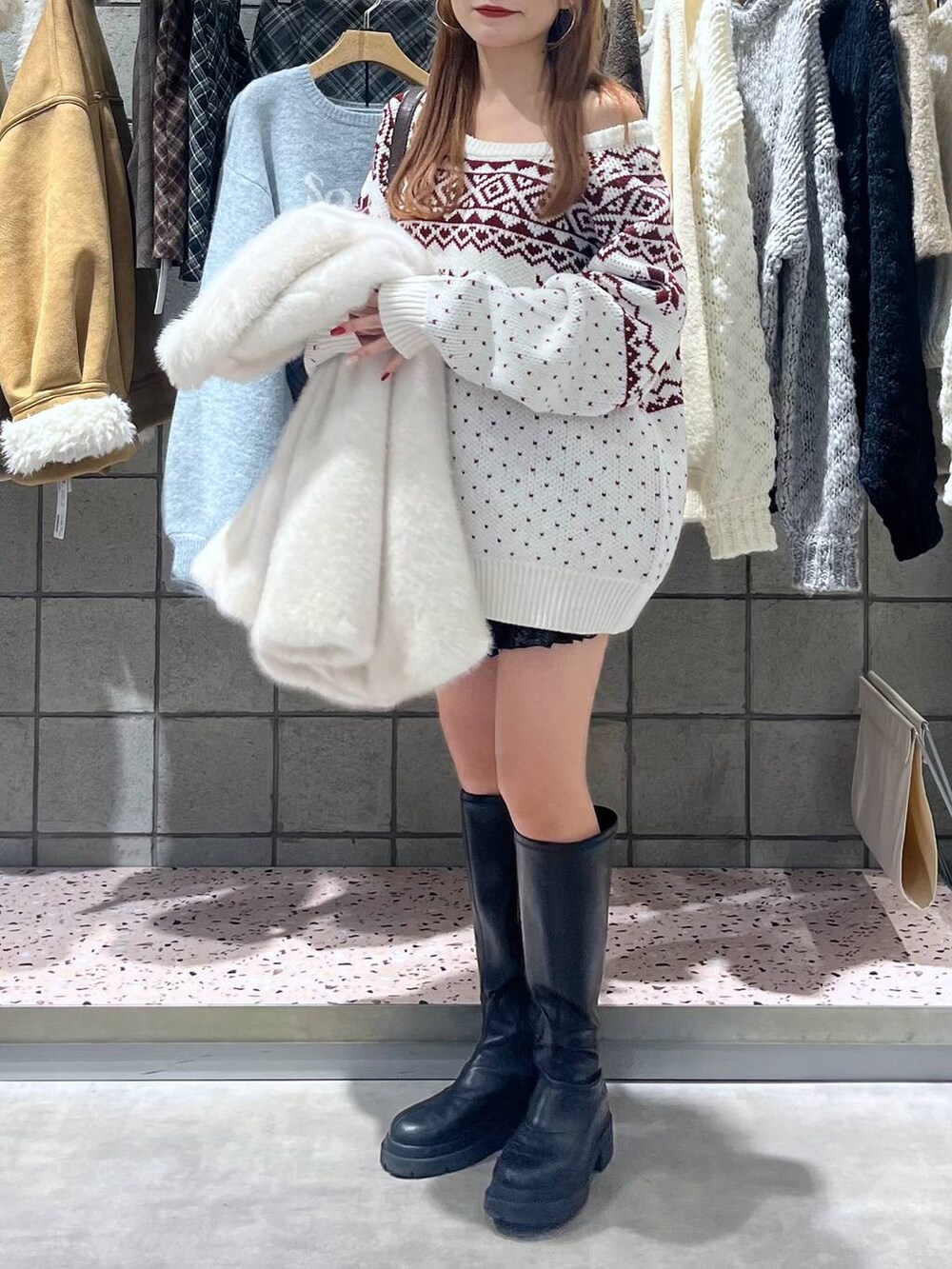 ブラック系のブーツ、ブラック系のスカート、ブラック系のショルダーバッグを着用したレディースの冬コーディネートの3枚目の写真