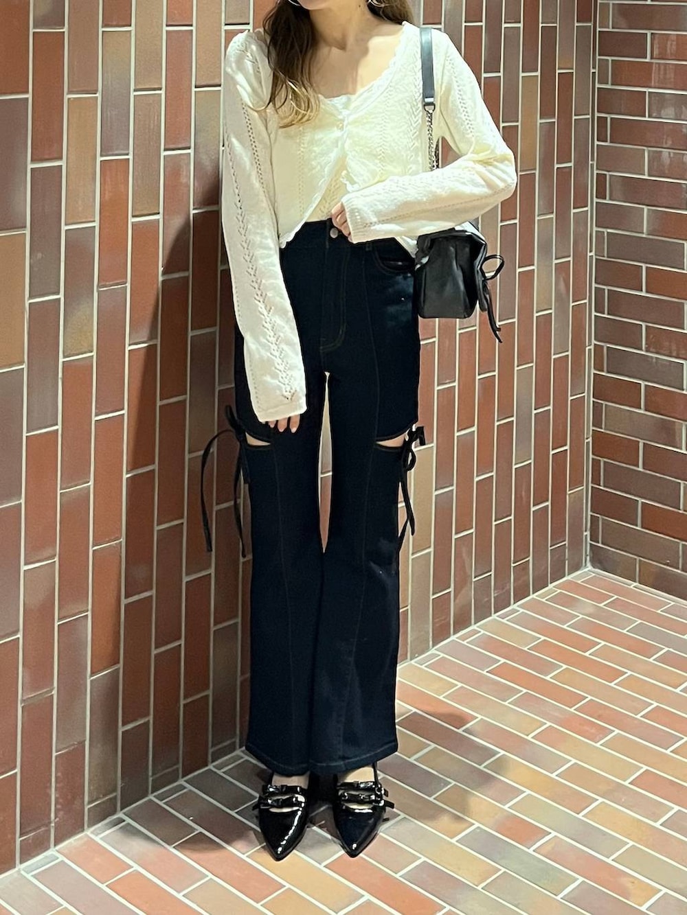 グレー系のショルダーバッグ、ブラック系のパンプス、ブルー系のデニムパンツを着用したレディースの春コーディネートの3枚目の写真