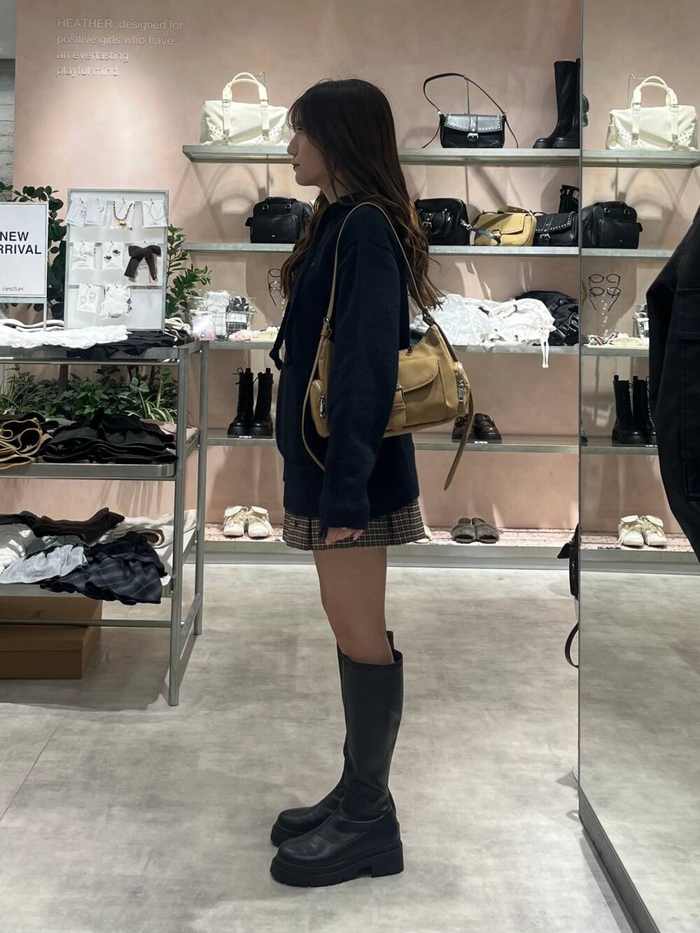 イエロー系のショルダーバッグ、ブラック系のブーツ、ブルー系のニット/セーターを着用したレディースの秋コーディネートの3枚目の写真