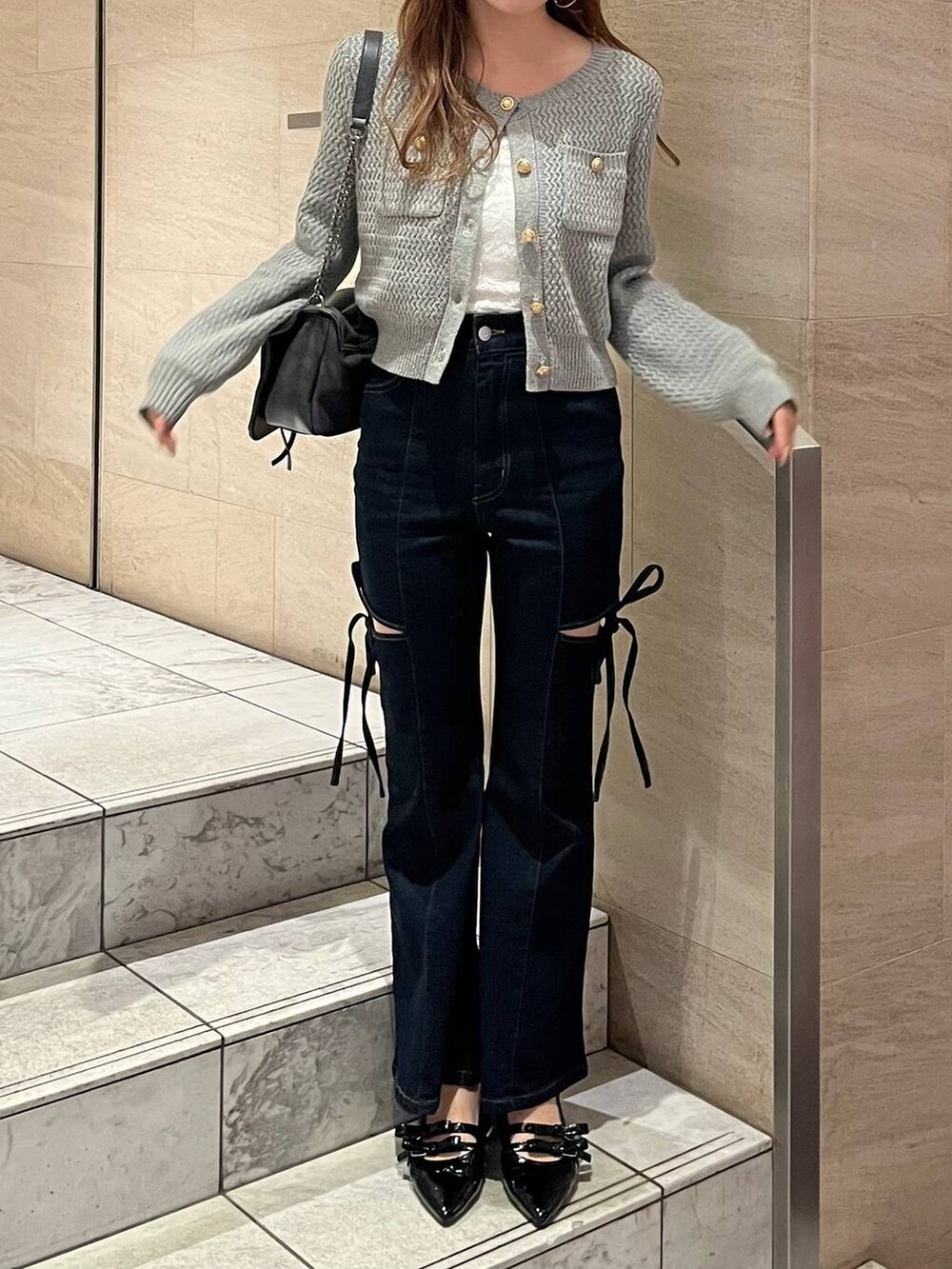 グレー系のショルダーバッグ、ブラック系のパンプス、ブルー系のデニムパンツを着用したレディースの春コーディネートの4枚目の写真