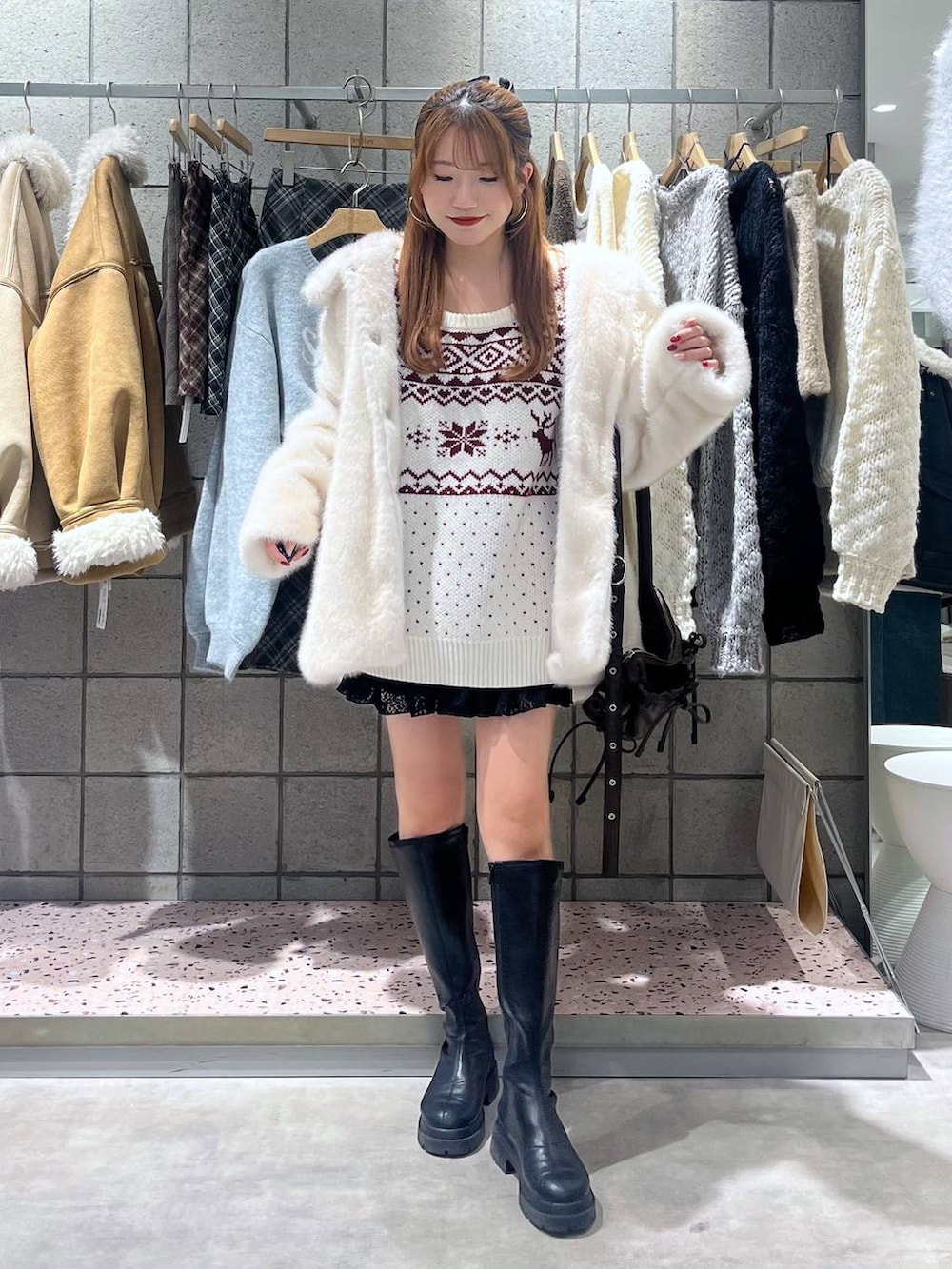 ブラック系のブーツ、ブラック系のスカート、ブラック系のショルダーバッグを着用したレディースの冬コーディネートの2枚目の写真