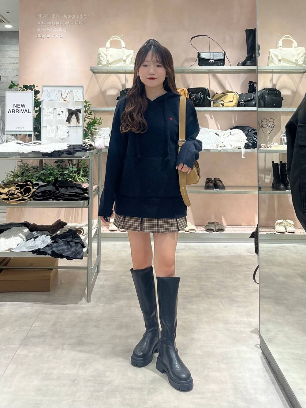 イエロー系のショルダーバッグ、ブラック系のブーツ、ブルー系のニット/セーターを着用したレディースの秋コーディネートの2枚目の写真