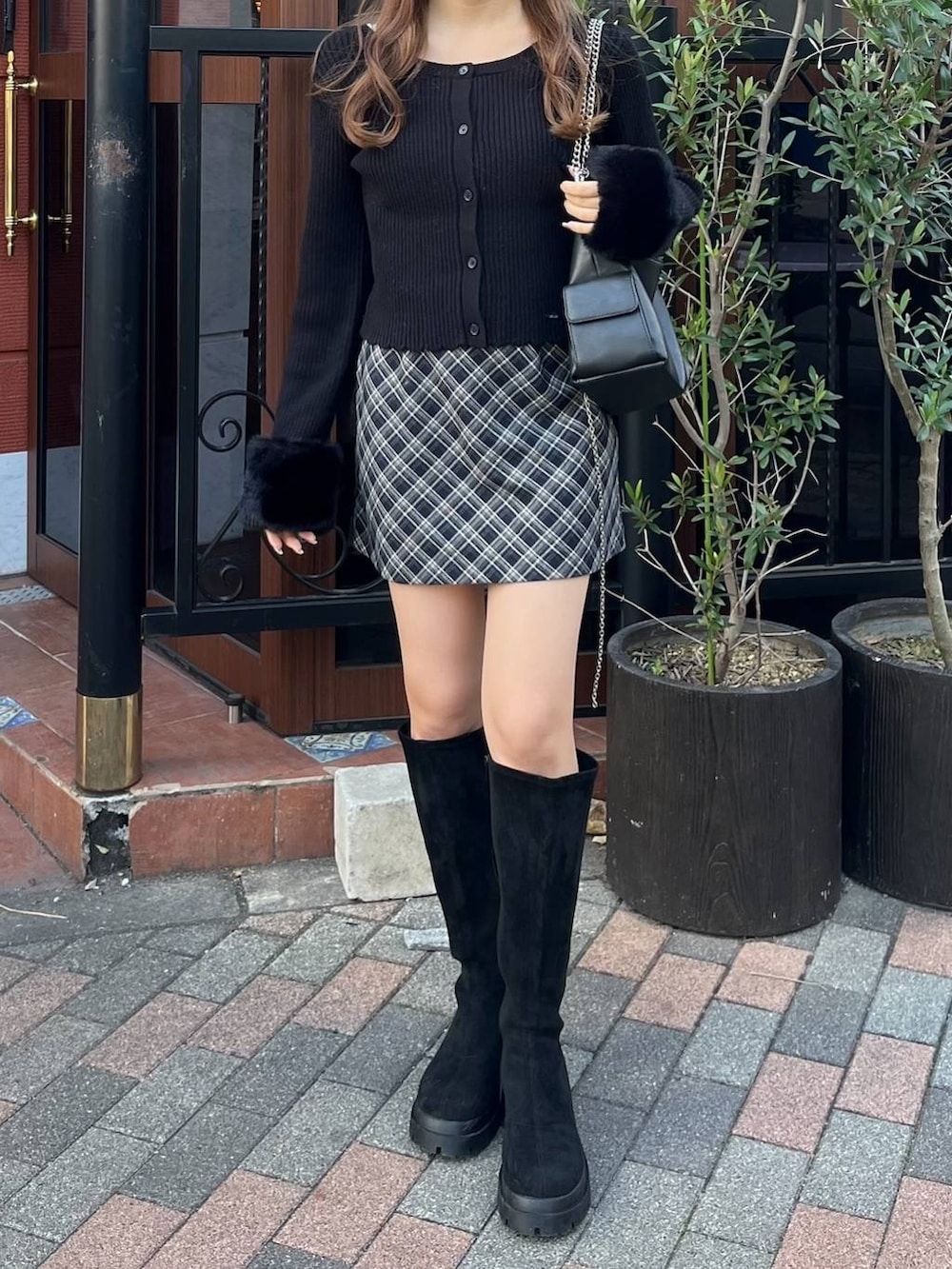 ブラック系のブーツ、ブルー系のスカート、ブラック系のショルダーバッグを着用したレディースの冬コーディネートの3枚目の写真