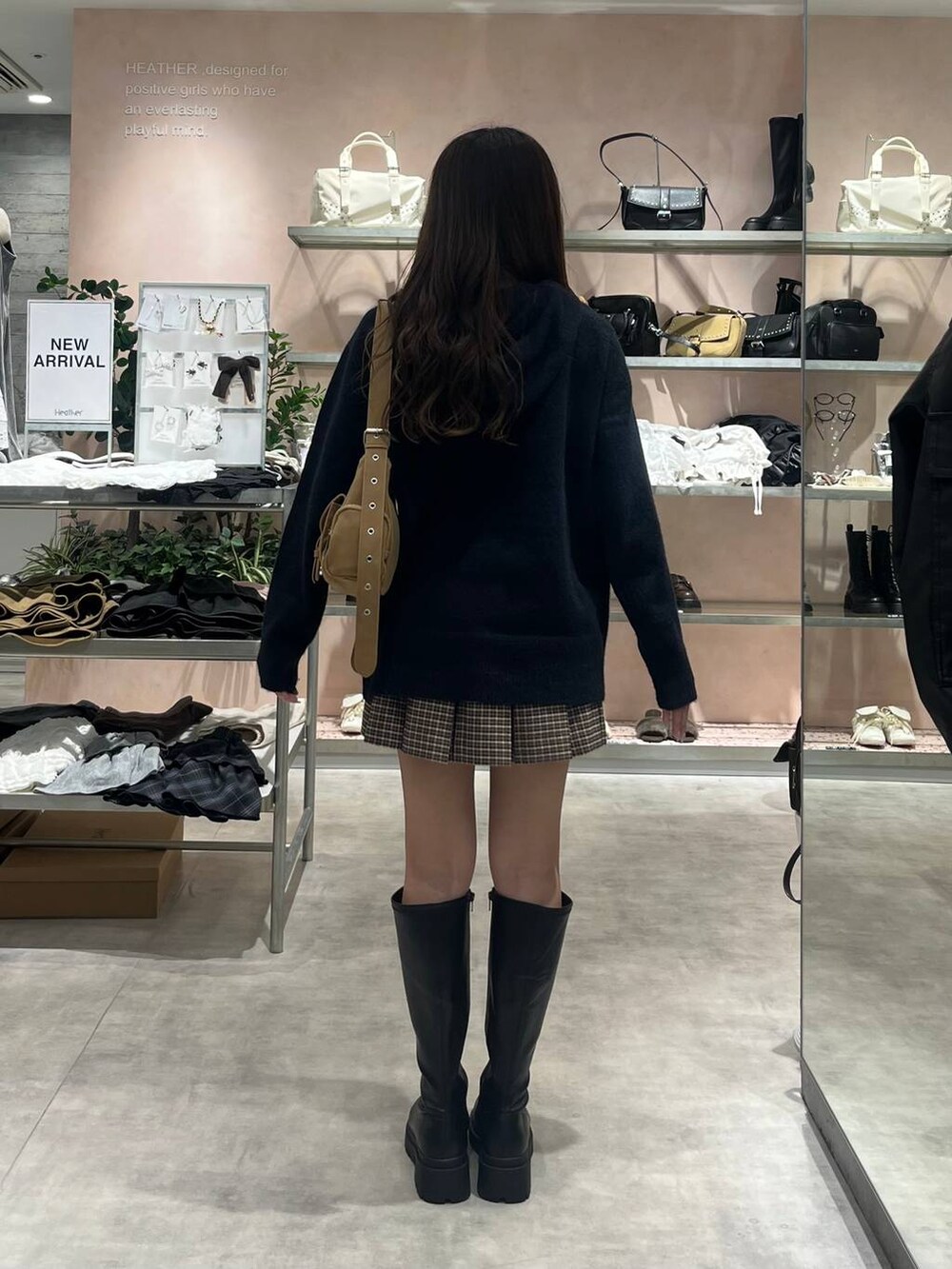 イエロー系のショルダーバッグ、ブラック系のブーツ、ブルー系のニット/セーターを着用したレディースの秋コーディネートの4枚目の写真