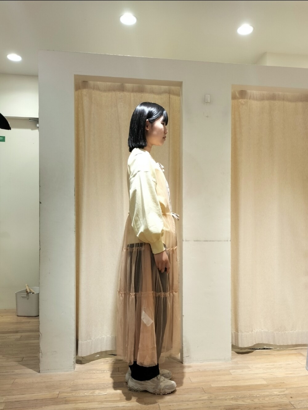 ブルー系のデニムパンツ、オレンジ系のワンピースを着用したレディースの春コーディネートの2枚目の写真