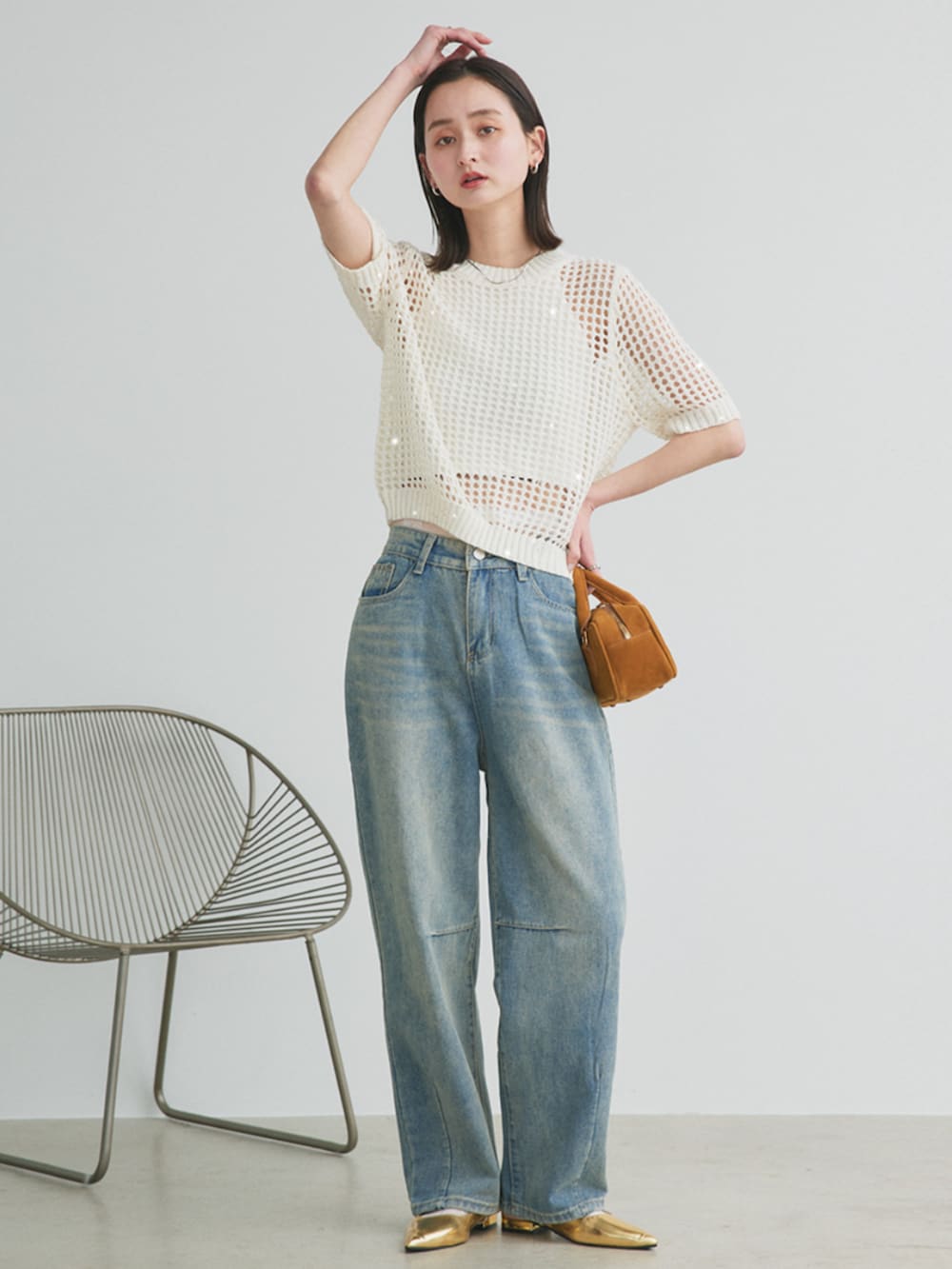 イエロー系のショルダーバッグ、ホワイト系のニット/セーター、ブルー系のデニムパンツを着用したレディースの春コーディネートの2枚目の写真