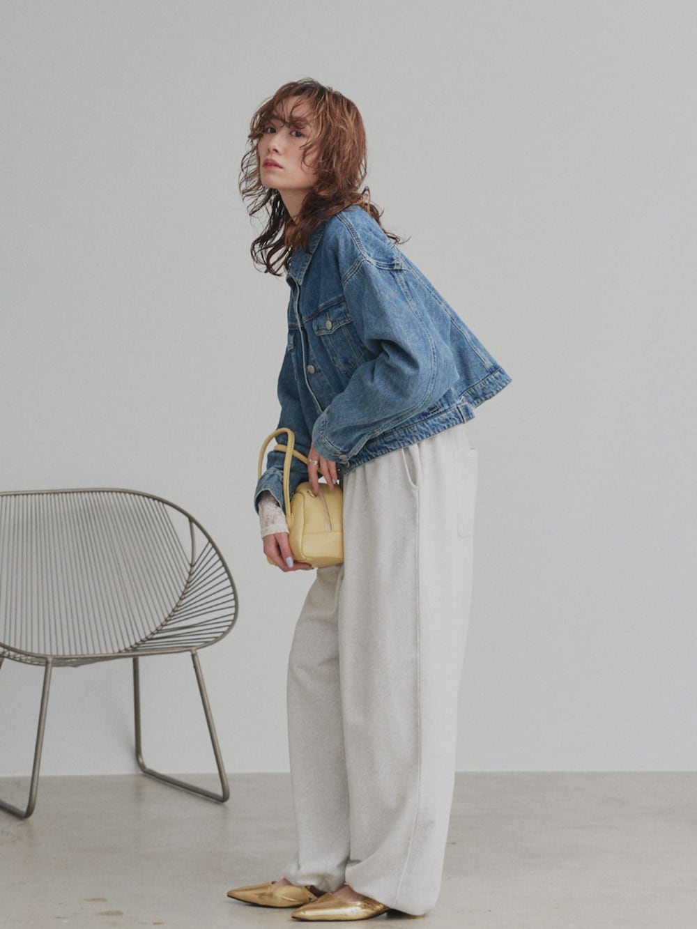 ベージュ系のスウェットパンツ、ブルー系のデニムジャケットを着用したレディースの冬コーディネートの2枚目の写真