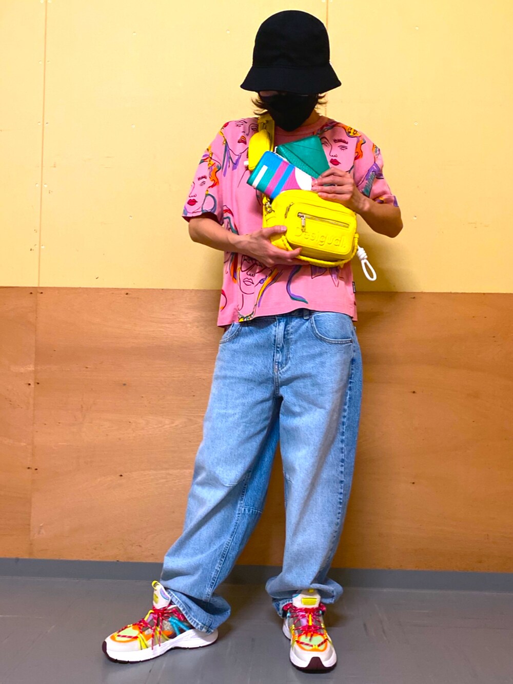 ブルー系のデニムパンツ、イエロー系のボディバッグ/ウエストポーチ、グリーン系の財布を着用したレディースの春コーディネートの2枚目の写真