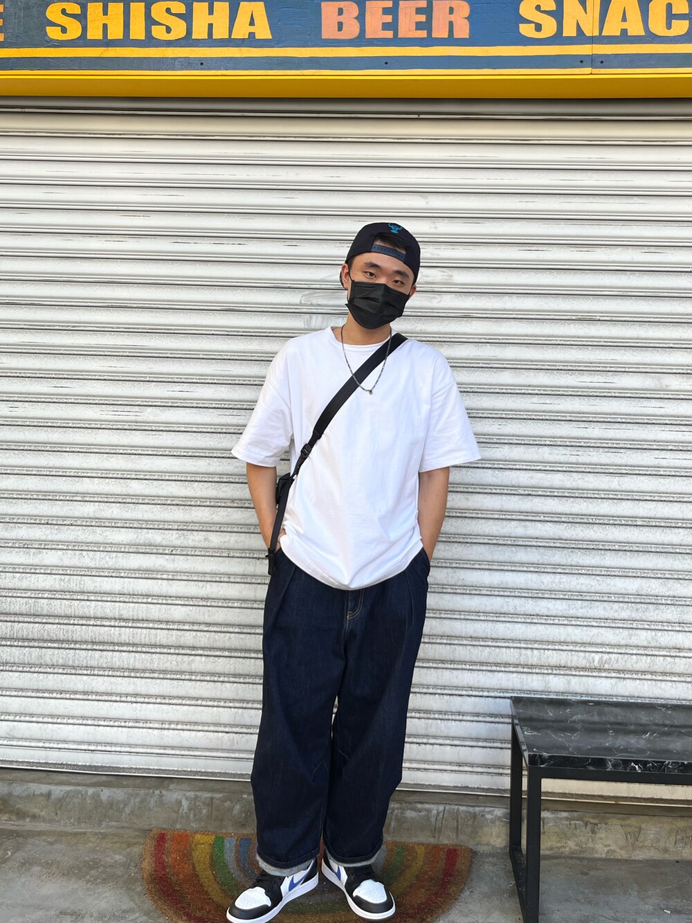 ホワイト系のTシャツ/カットソー、ブラック系のメッセンジャーバッグ、ブルー系のデニムパンツを着用したメンズの秋コーディネートの3枚目の写真