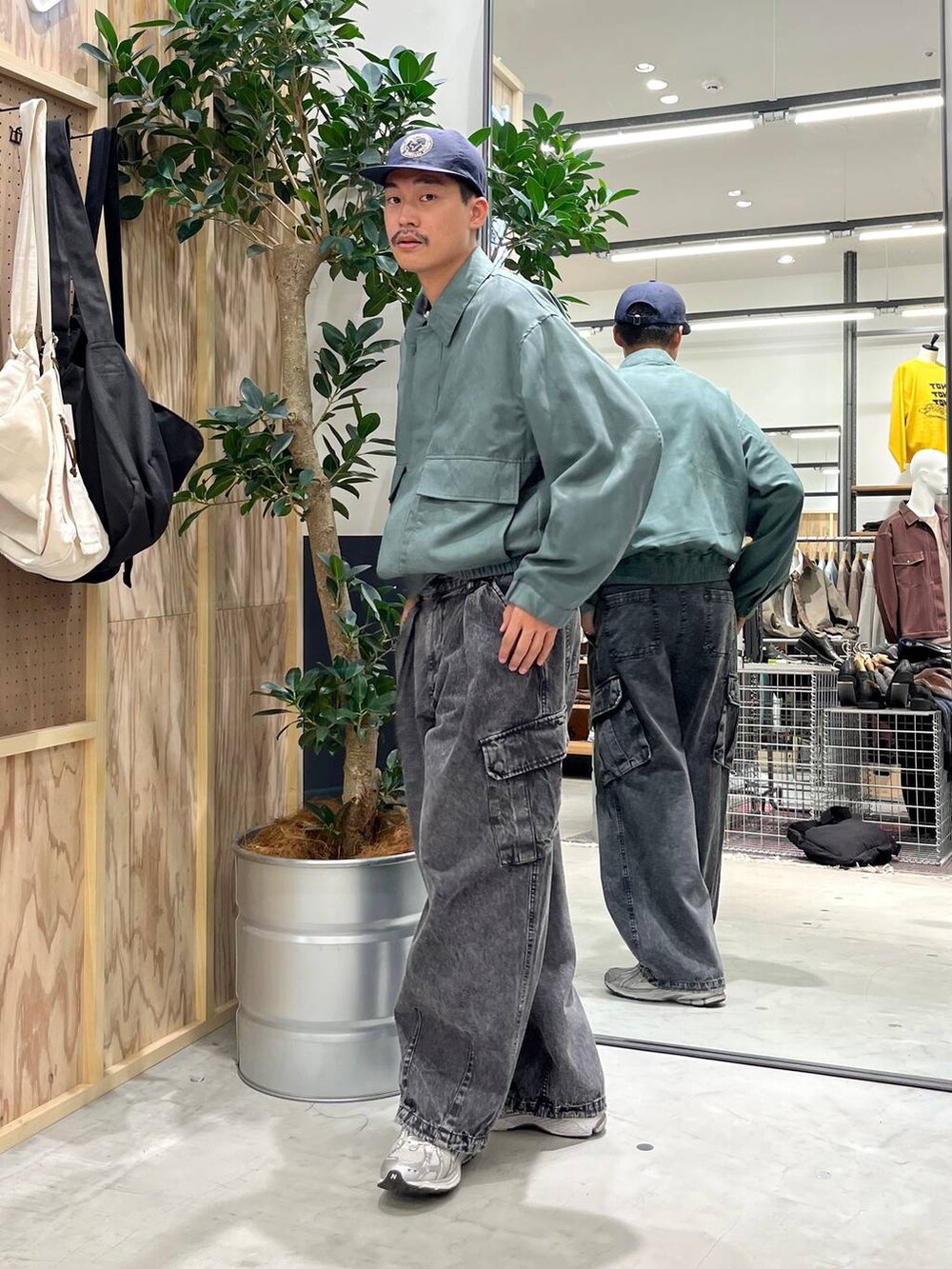 グレー系のデニムパンツ、ホワイト系のTシャツ/カットソー、グリーン系のブルゾンを着用したメンズの秋コーディネートの4枚目の写真