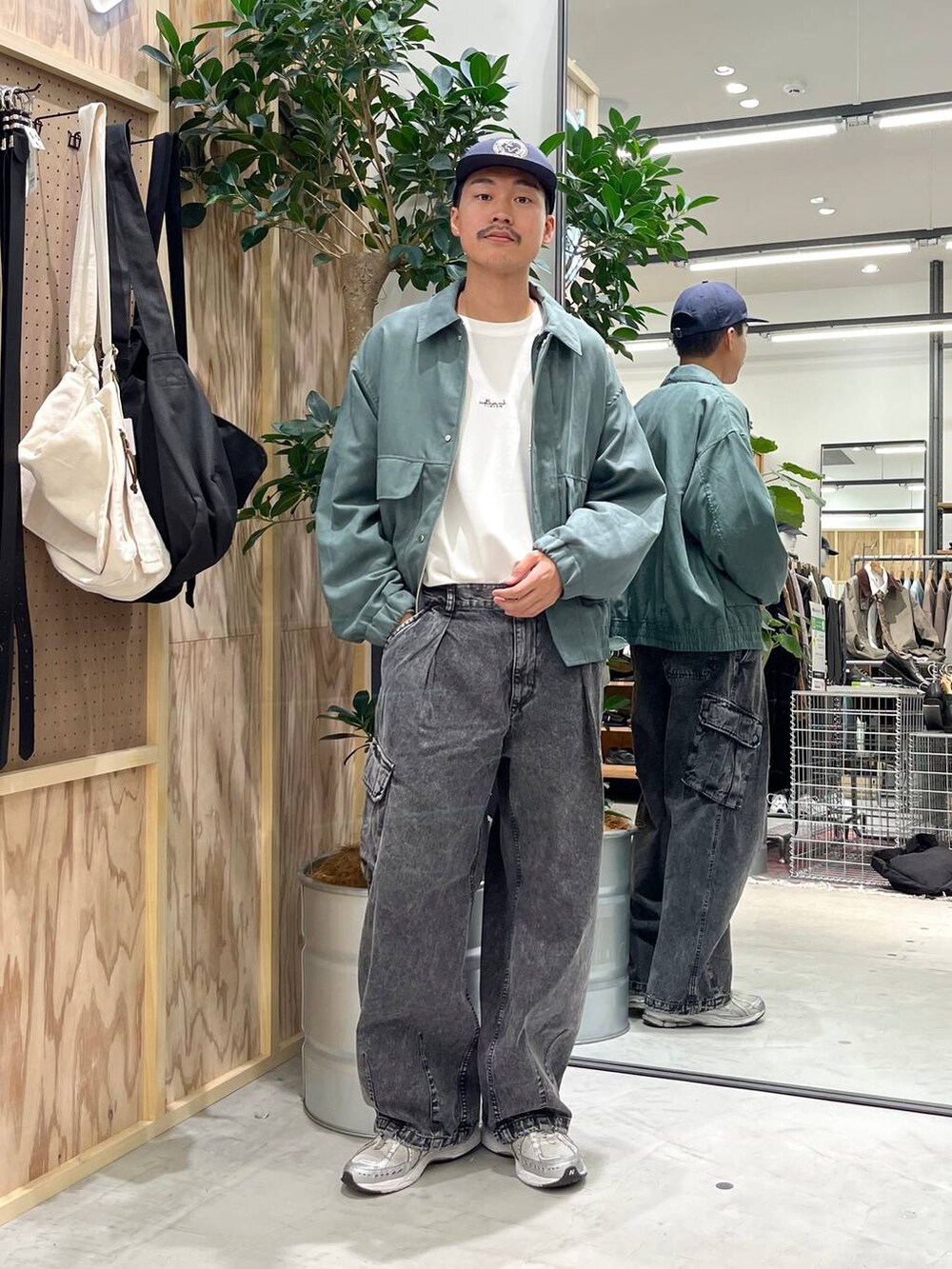グレー系のデニムパンツ、ホワイト系のTシャツ/カットソー、グリーン系のブルゾンを着用したメンズの秋コーディネートの2枚目の写真