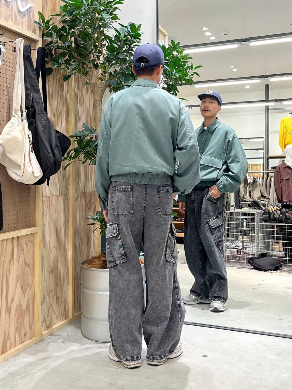 グレー系のデニムパンツ、ホワイト系のTシャツ/カットソー、グリーン系のブルゾンを着用したメンズの秋コーディネートの5枚目の写真