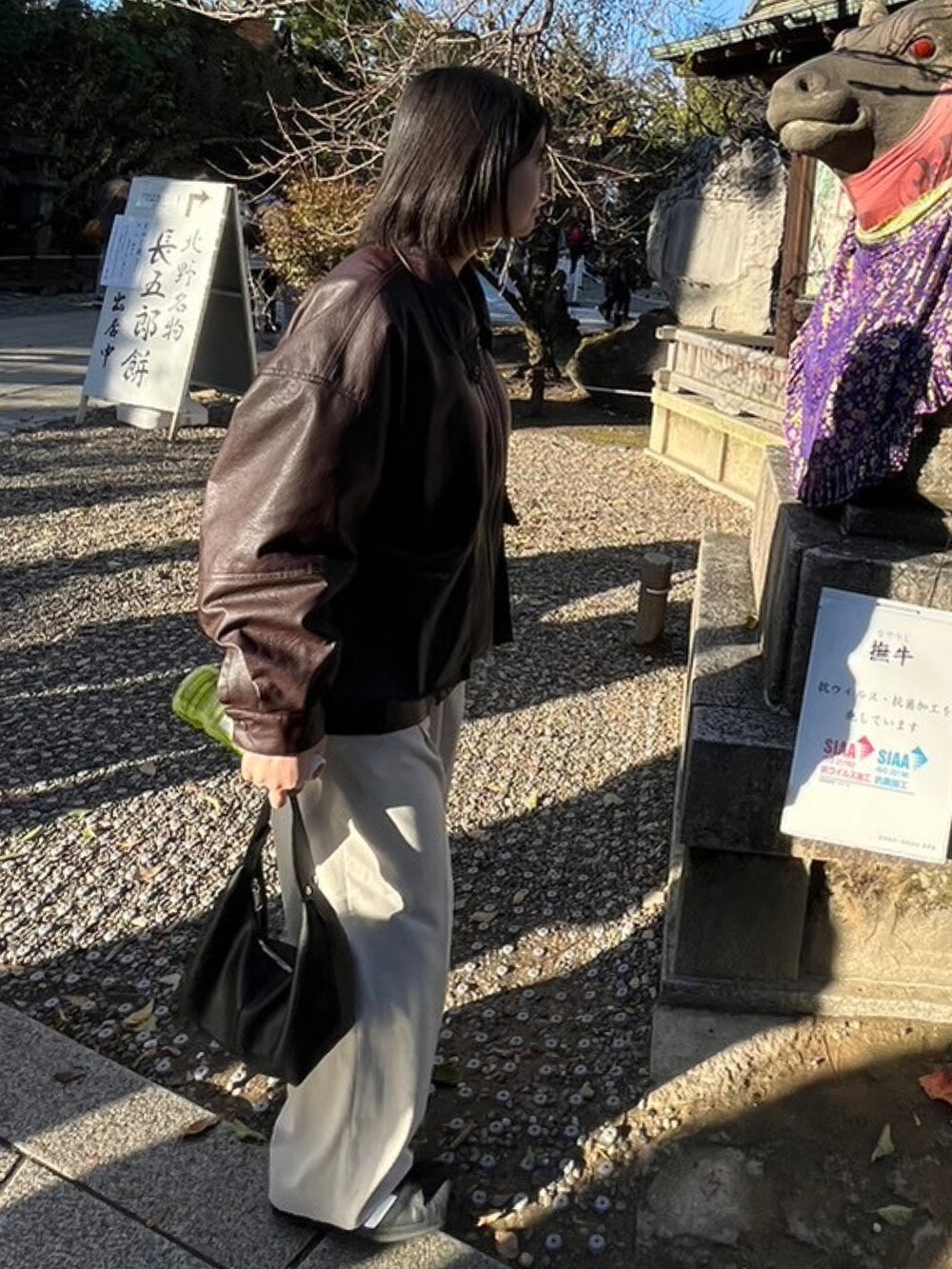 ブラウン系のブルゾン、ホワイト系のスニーカー、ホワイト系のスラックスを着用したレディースの秋コーディネートの2枚目の写真