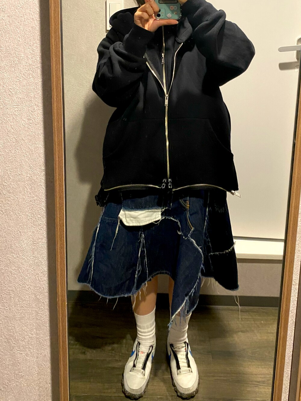 ブラック系のパーカー、ブルー系のスカートを着用したレディースの冬コーディネートの2枚目の写真