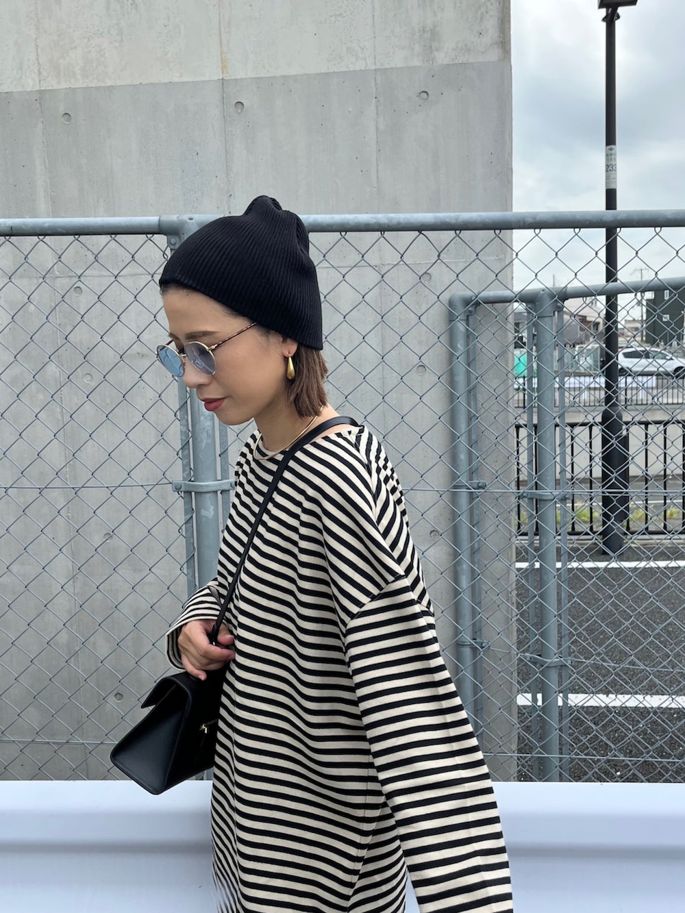 ベージュ系のTシャツ/カットソー、ブラック系のバッグ、ブラック系のブーツを着用したレディースの秋コーディネートの2枚目の写真