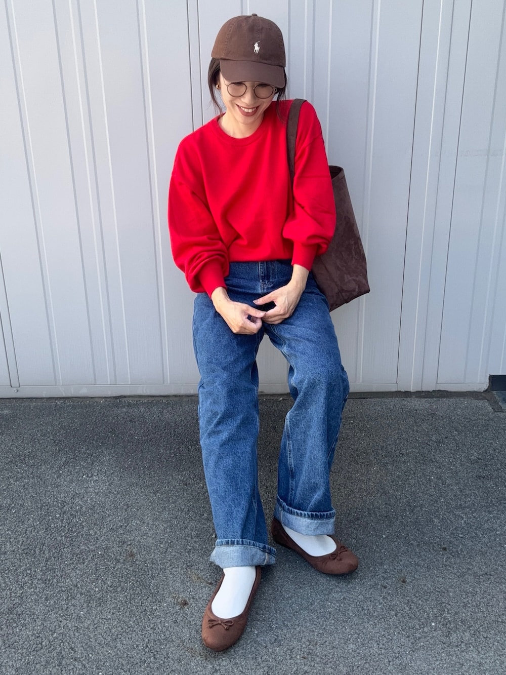 レッド系のニット/セーター、ブルー系のデニムパンツ、ブラウン系のパンプスを着用したレディースの秋コーディネートの3枚目の写真