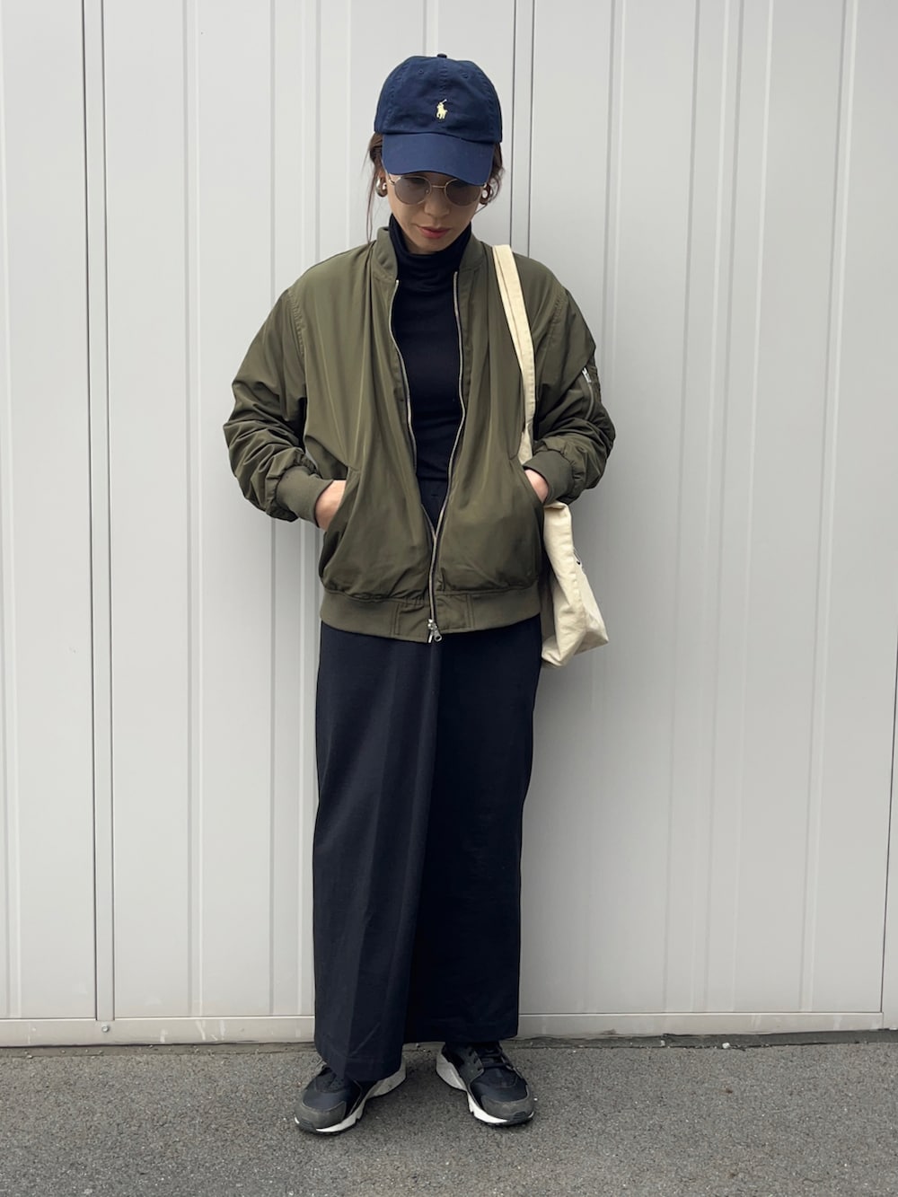 グリーン系のMA-1、ブラック系のスニーカー、グレー系のサングラスを着用したレディースの春コーディネートの2枚目の写真