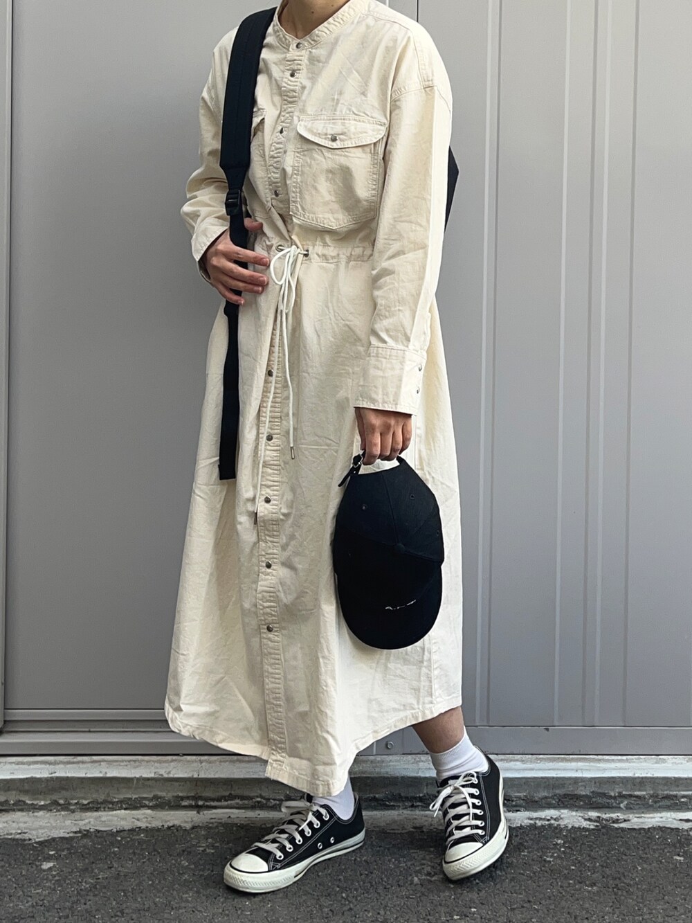 ホワイト系のシャツワンピース、ブラック系のバックパック/リュック、ブラック系のキャップを着用したレディースの冬コーディネートの2枚目の写真