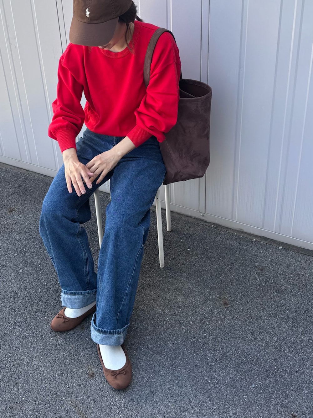 レッド系のニット/セーター、ブルー系のデニムパンツ、ブラウン系のパンプスを着用したレディースの秋コーディネートの4枚目の写真