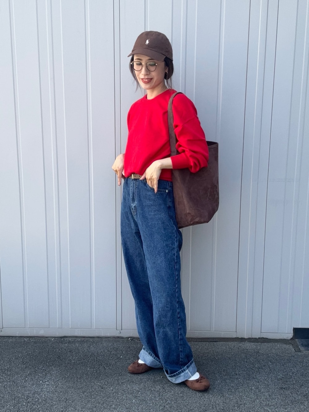 レッド系のニット/セーター、ブルー系のデニムパンツ、ブラウン系のパンプスを着用したレディースの秋コーディネートの2枚目の写真