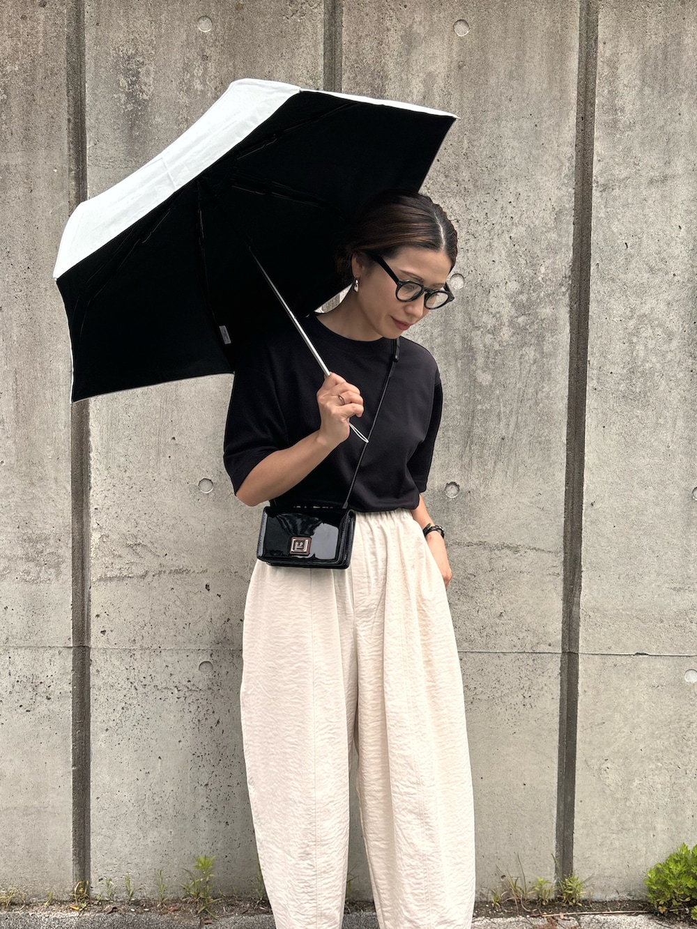 ホワイト系のチノパンツ、ブラック系のサンダル、ホワイト系の折りたたみ傘を着用したレディースの春コーディネートの2枚目の写真