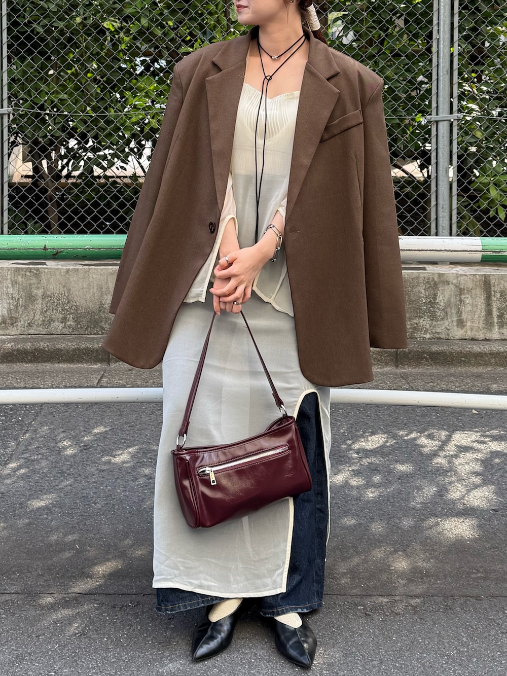 ホワイト系のキャミソール、レッド系のショルダーバッグ、ブラウン系のテーラードジャケットを着用したレディースの秋コーディネートの2枚目の写真