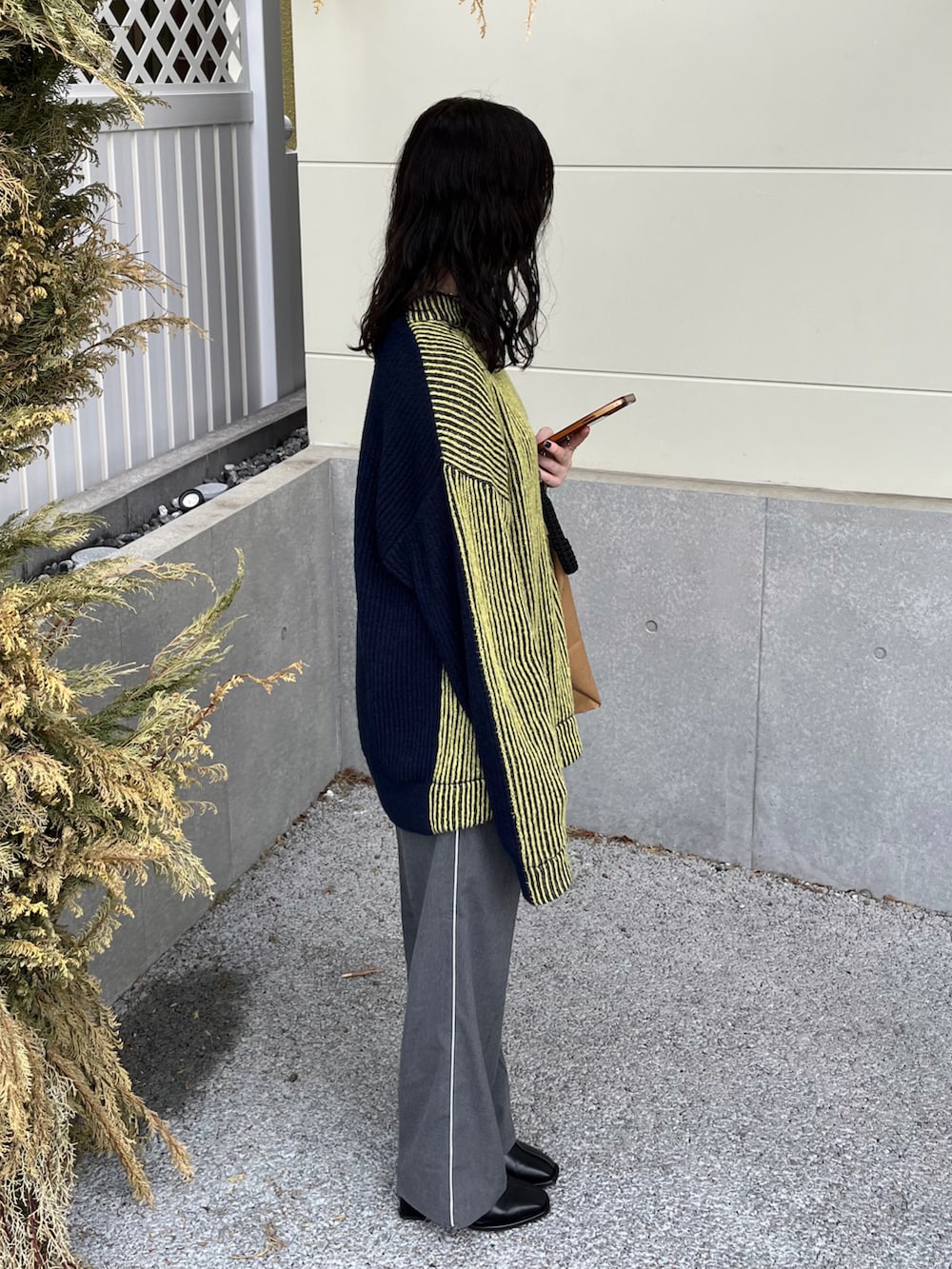 イエロー系のニット/セーター、グレー系のその他パンツ、ブラック系のショルダーバッグを着用したレディースの冬コーディネートの4枚目の写真