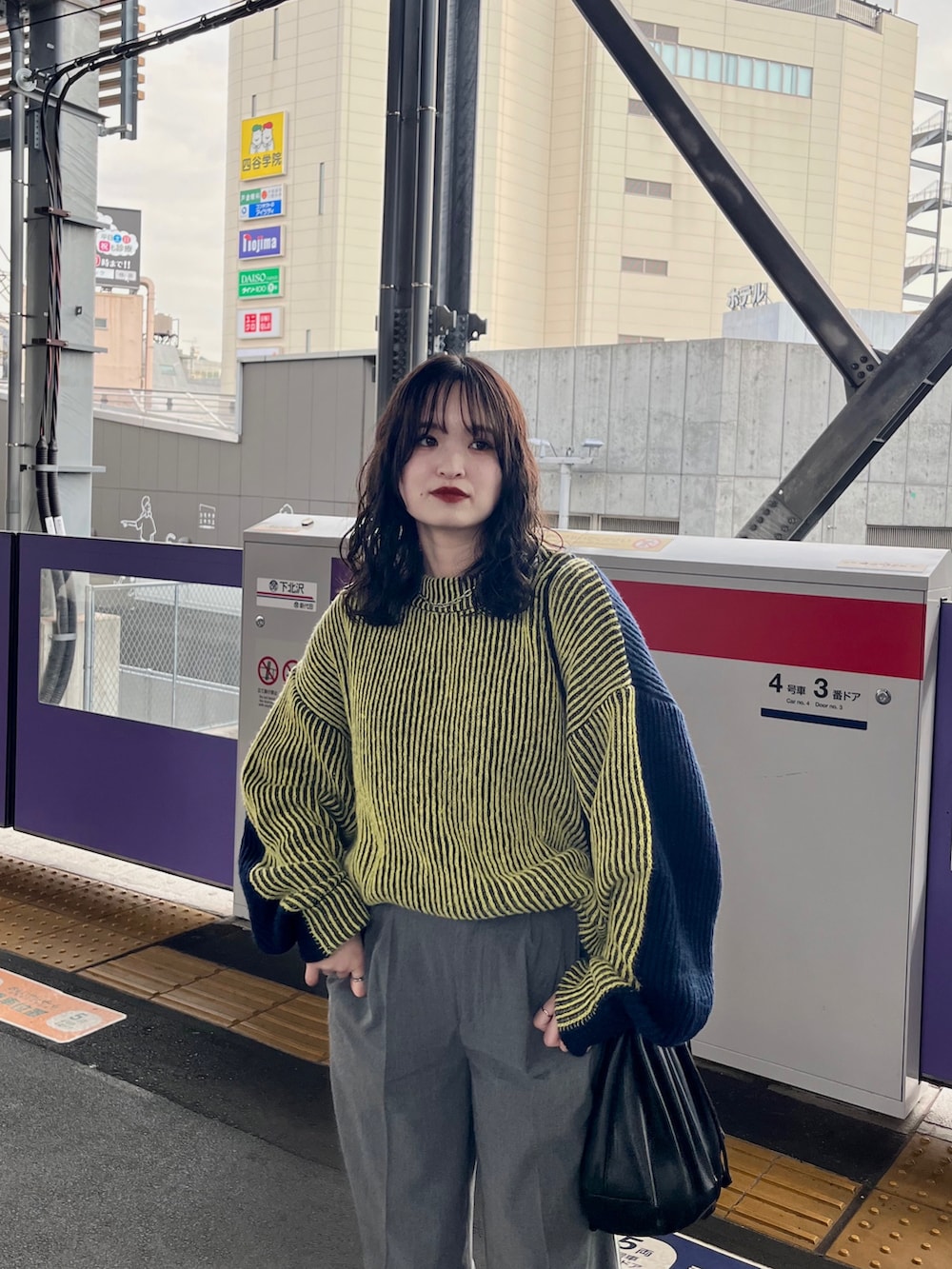 イエロー系のニット/セーター、グレー系のその他パンツ、ブラック系のショルダーバッグを着用したレディースの冬コーディネートの5枚目の写真