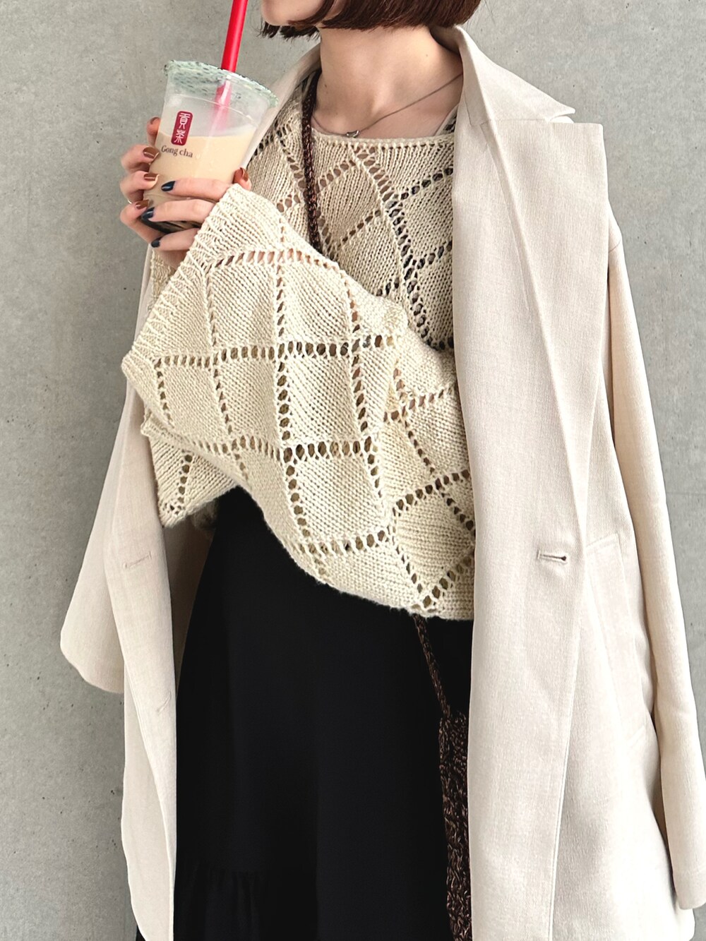 ホワイト系のテーラードジャケット、ホワイト系のニット/セーター、ブラウン系のショルダーバッグを着用したレディースの春コーディネートの2枚目の写真