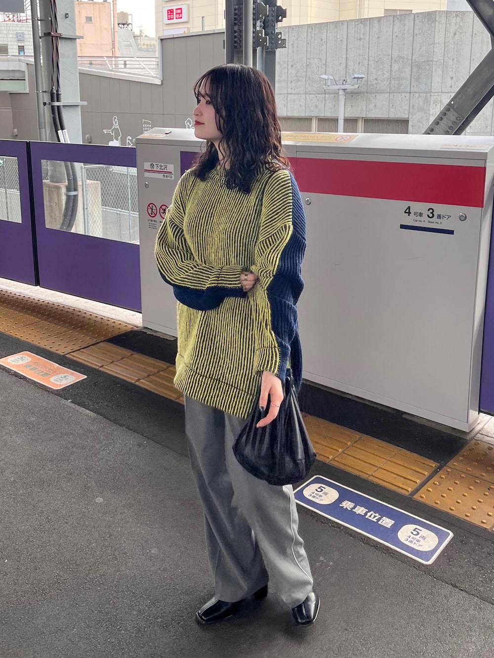 イエロー系のニット/セーター、グレー系のその他パンツ、ブラック系のショルダーバッグを着用したレディースの冬コーディネートの2枚目の写真