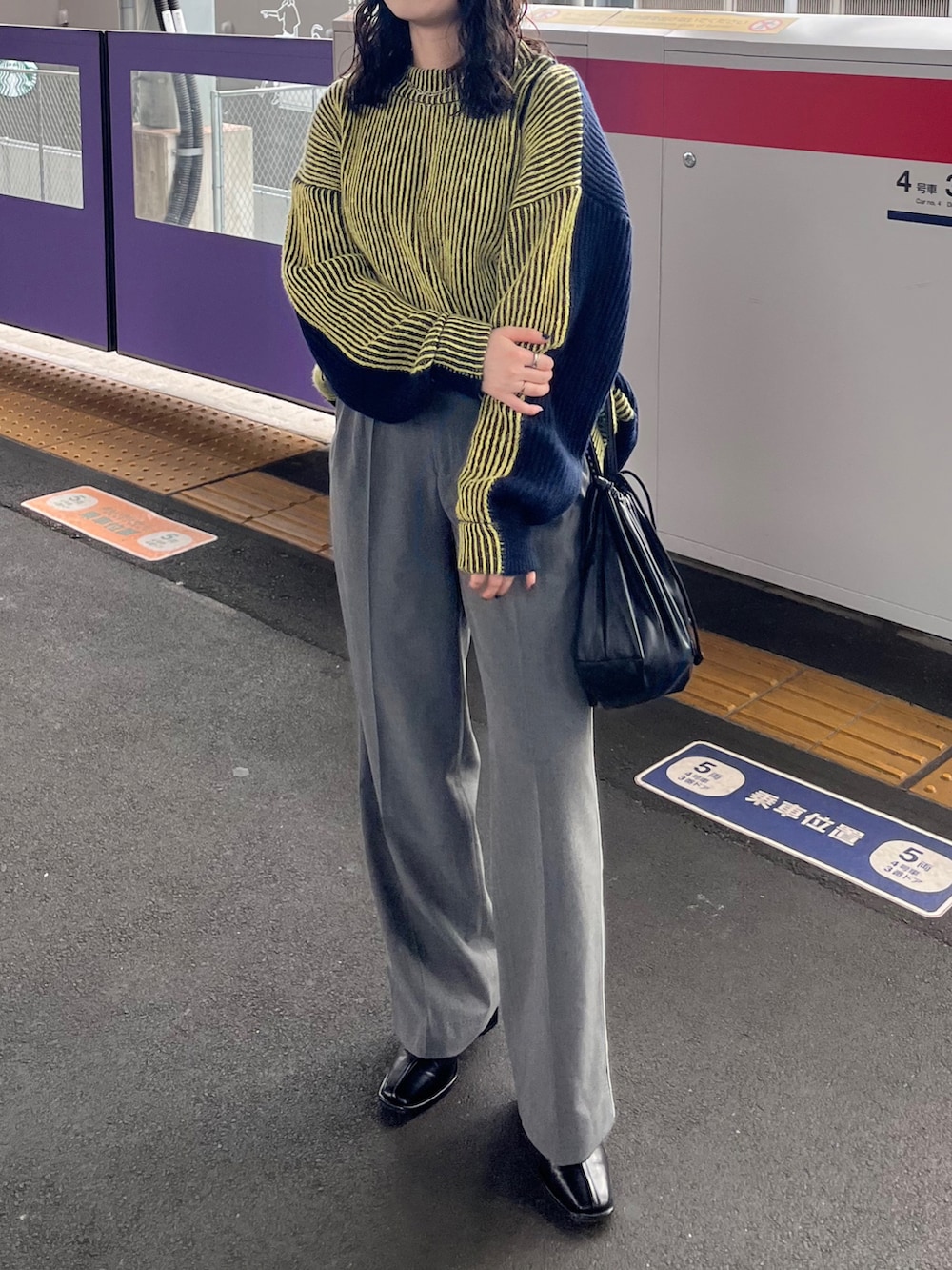 イエロー系のニット/セーター、グレー系のその他パンツ、ブラック系のショルダーバッグを着用したレディースの冬コーディネートの3枚目の写真