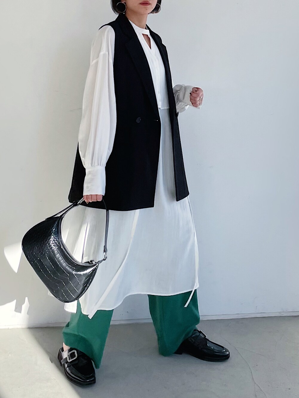 ホワイト系のワンピース、ブラック系のその他アウター、グリーン系のスラックスを着用したレディースの冬コーディネートの2枚目の写真