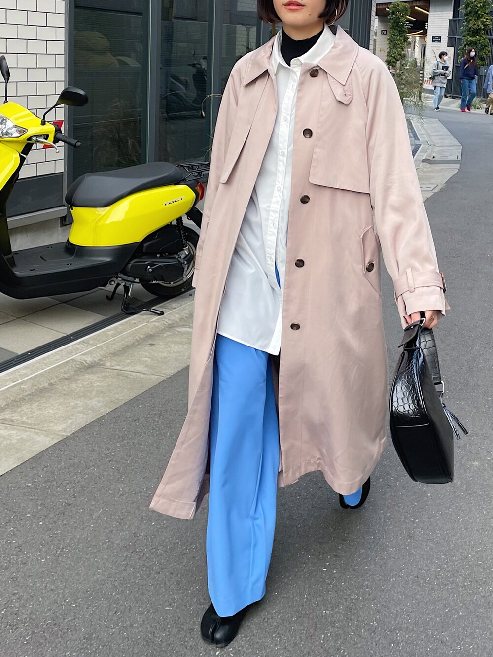 ベージュ系のトレンチコート、ホワイト系のシャツ/ブラウス、ブルー系のスラックスを着用したレディースの冬コーディネートの2枚目の写真