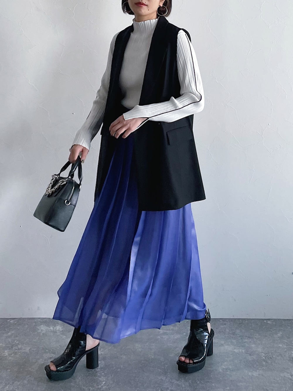 ホワイト系のニット/セーター、パープル系のスカート、ブラック系のその他アウターを着用したレディースの冬コーディネートの2枚目の写真