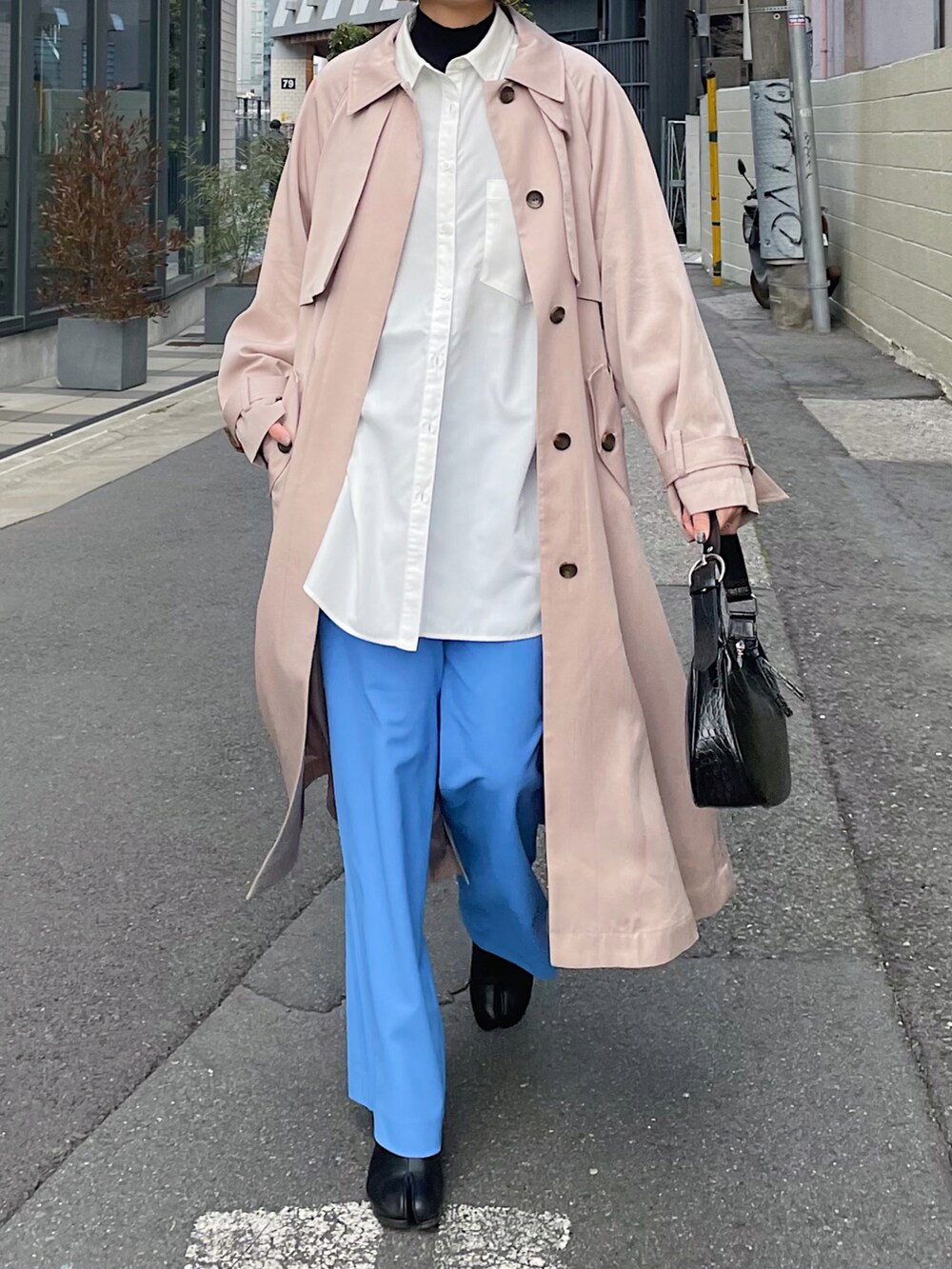 ベージュ系のトレンチコート、ホワイト系のシャツ/ブラウス、ブルー系のスラックスを着用したレディースの冬コーディネートの5枚目の写真