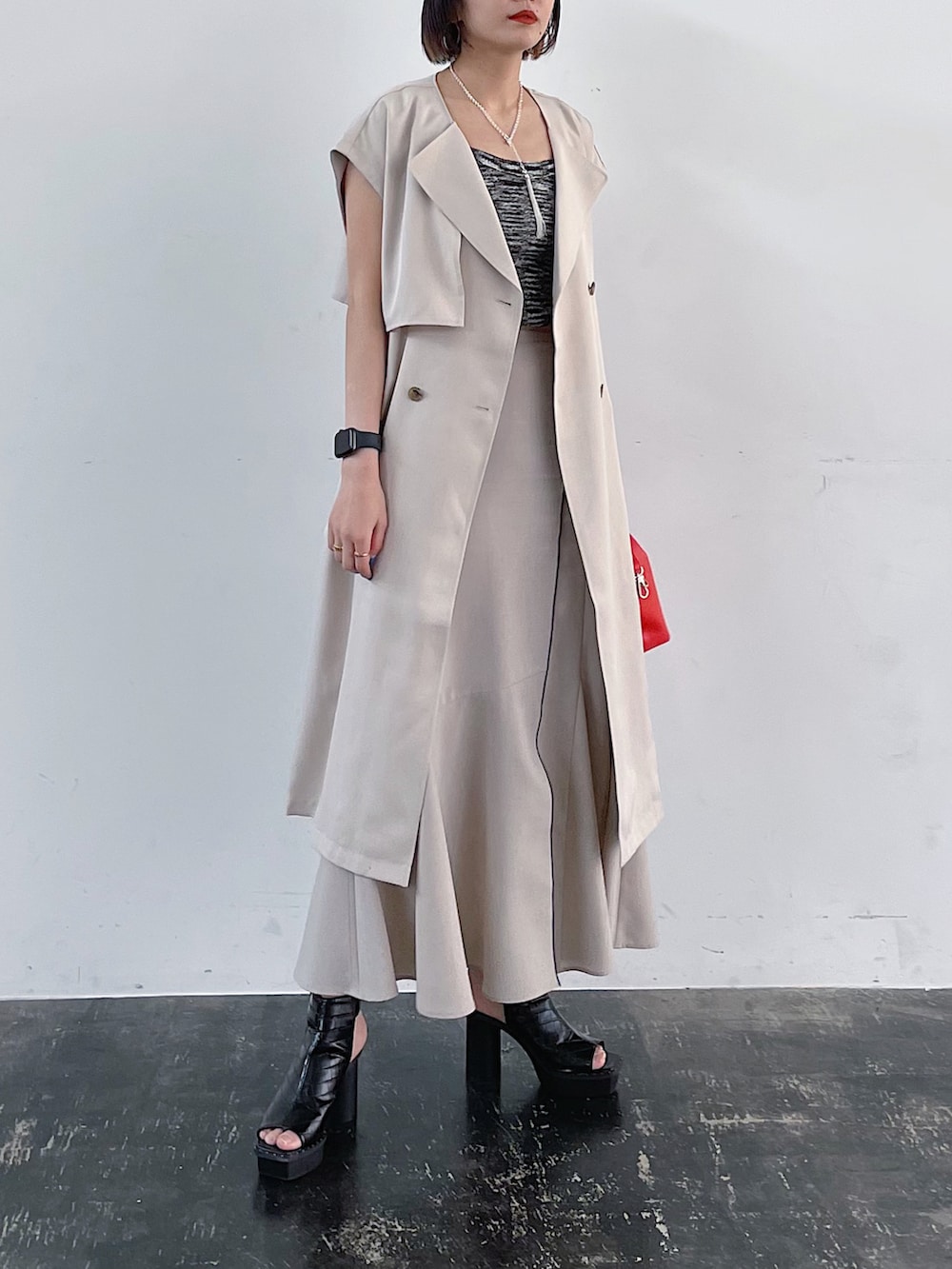 ベージュ系のその他アウター、オレンジ系のショルダーバッグ、ベージュ系のスカートを着用したレディースの春コーディネートの3枚目の写真