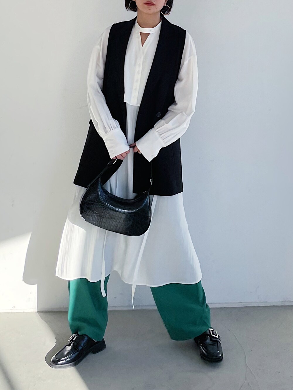 ホワイト系のワンピース、ブラック系のその他アウター、グリーン系のスラックスを着用したレディースの冬コーディネートの3枚目の写真