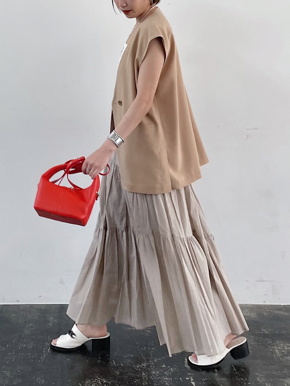 ベージュ系のテーラードジャケット、オレンジ系のショルダーバッグ、ベージュ系のスカートを着用したレディースの春コーディネートの3枚目の写真