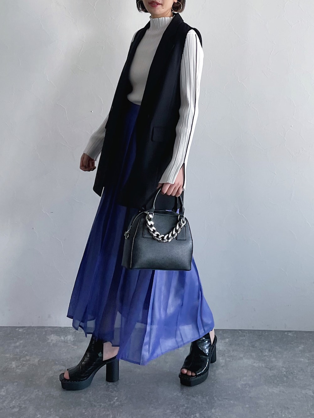 ホワイト系のニット/セーター、パープル系のスカート、ブラック系のその他アウターを着用したレディースの冬コーディネートの3枚目の写真