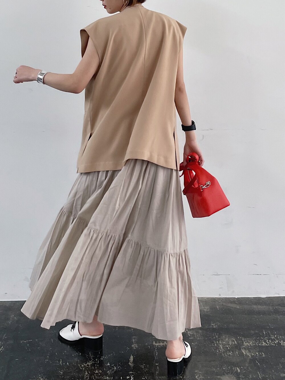 ベージュ系のテーラードジャケット、オレンジ系のショルダーバッグ、ベージュ系のスカートを着用したレディースの春コーディネートの4枚目の写真