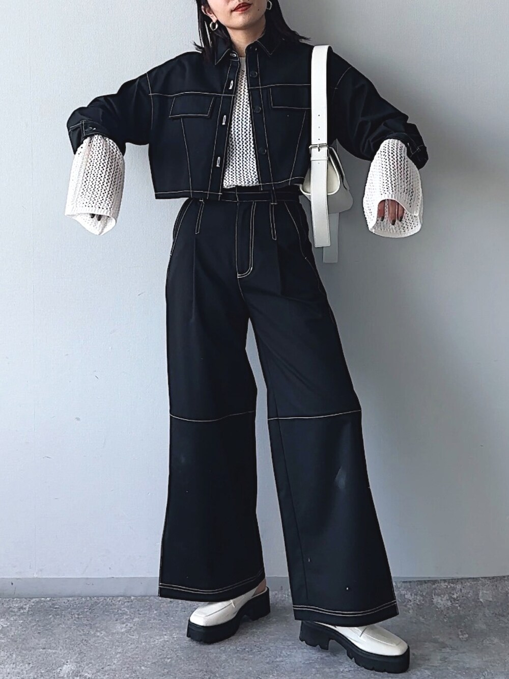 ブラック系のシャツ/ブラウス、ブラック系のスラックス、ホワイト系のニット/セーターを着用したレディースの冬コーディネートの2枚目の写真