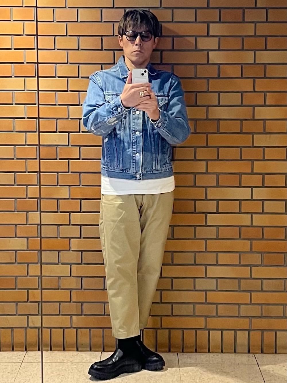 ブルー系のデニムジャケット、ベージュ系のチノパンツ、シルバー系のリングを着用したメンズの秋コーディネートの2枚目の写真