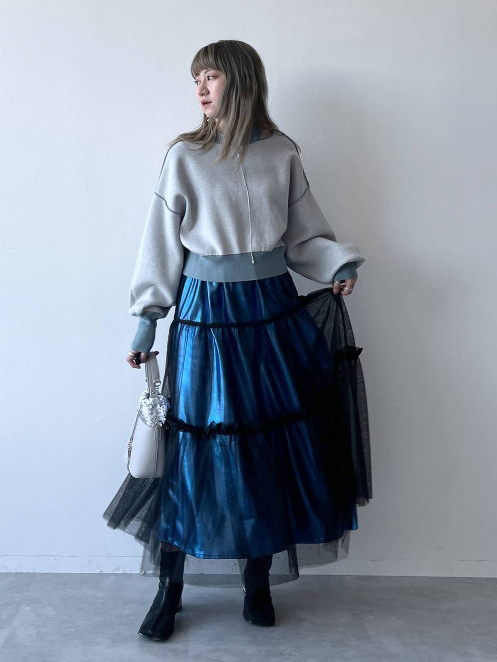 ブルー系のカーディガン/ボレロ、ブルー系のスカート、ホワイト系のショルダーバッグを着用したレディースの冬コーディネートの5枚目の写真