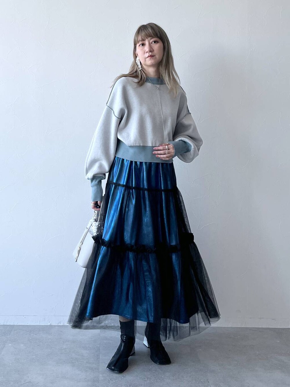 ブルー系のカーディガン/ボレロ、ブルー系のスカート、ホワイト系のショルダーバッグを着用したレディースの冬コーディネートの3枚目の写真