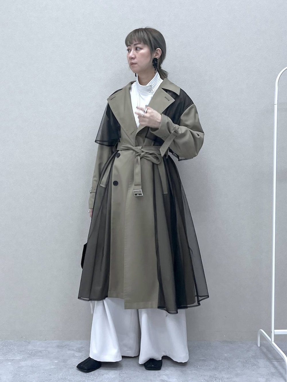 ベージュ系のトレンチコート、ブラック系のショルダーバッグ、ホワイト系のシャツ/ブラウスを着用したレディースの冬コーディネートの2枚目の写真