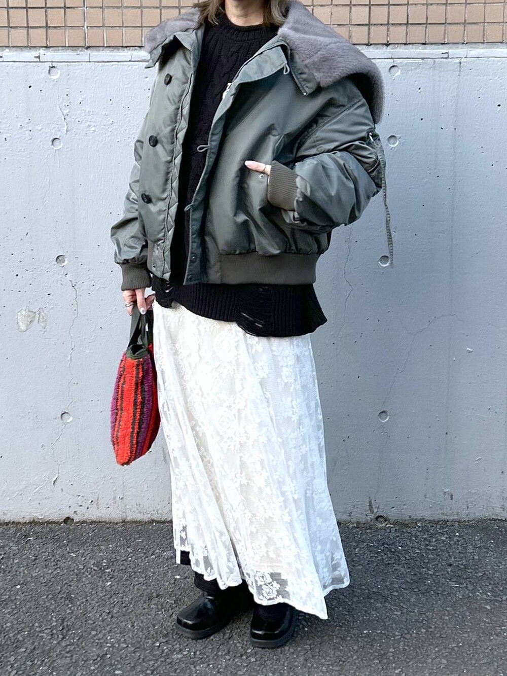グリーン系のブルゾン、ブラック系のブーツ、ホワイト系のワンピースを着用したレディースの冬コーディネートの8枚目の写真